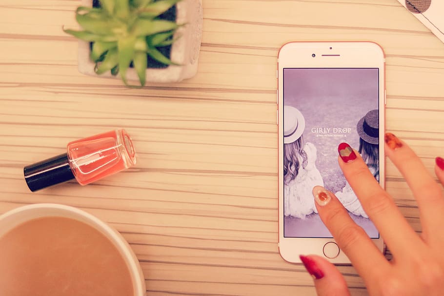 person with red manicure touching screen of rose gold iPhone 6s HD wallpaper