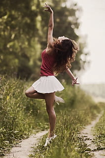 woman in pink top and white pleated mini skirt doing dance gesture on grass covered pathway HD wallpaper