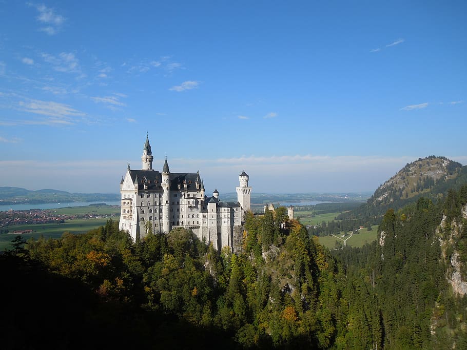 white concrete castle on hills surrounded by trees during daytime HD wallpaper