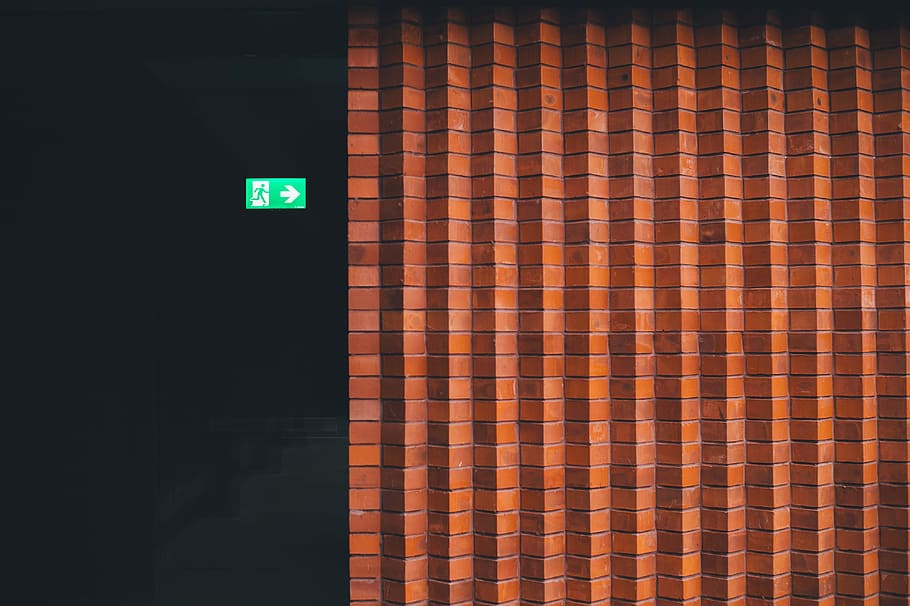 Small green exit sign pointing towards brick wall at Whitworth Art Gallery, brown concrete bricked wall HD wallpaper