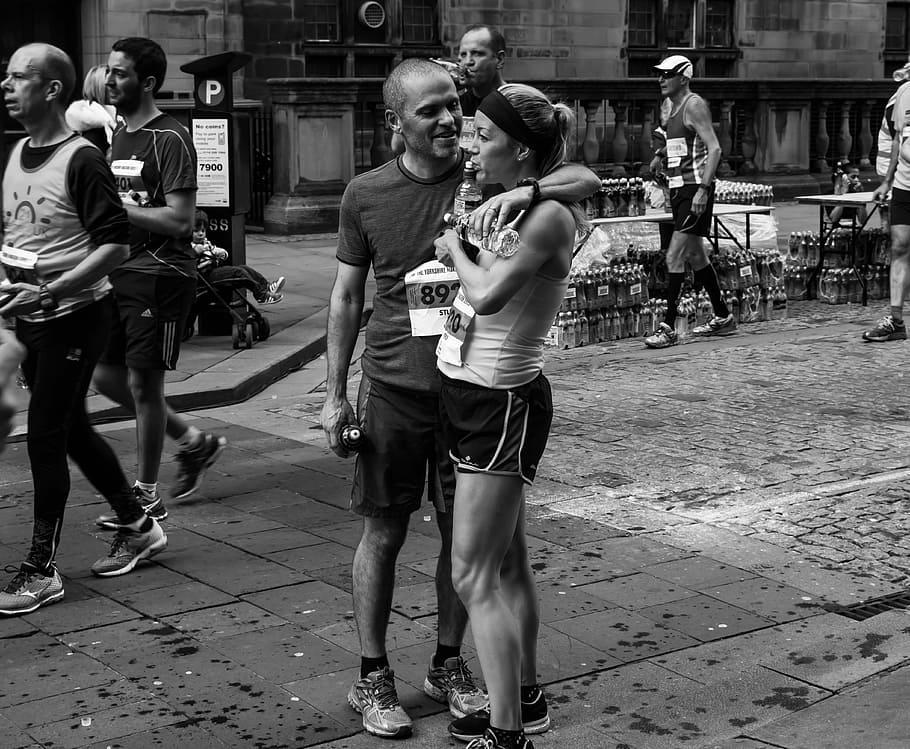 grayscale photo of man and woman standing at the road, Marathon