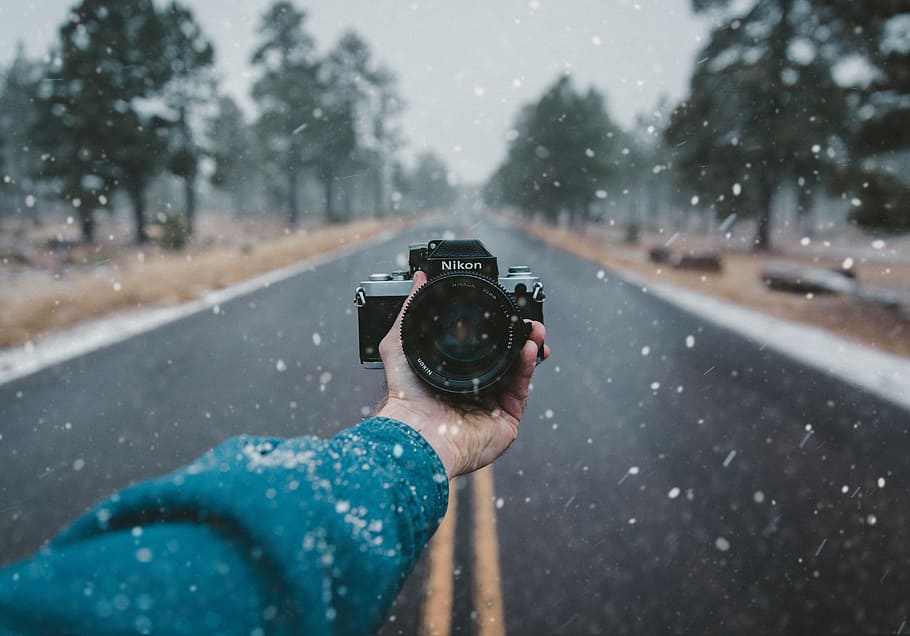 person holding Nikon DSLR camera, person holding Nikon camera on road over pouring snow HD wallpaper