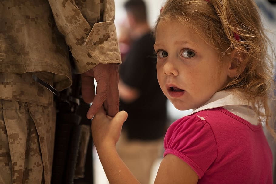 girl in pink shirt holding hand of woman, soldier, daughter, child