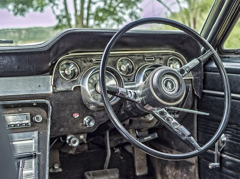 closeup photograph of steering wheel and car radio, old, odometer