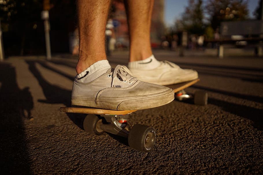 person wearing white Vans Authentic riding skateboard, outdoors
