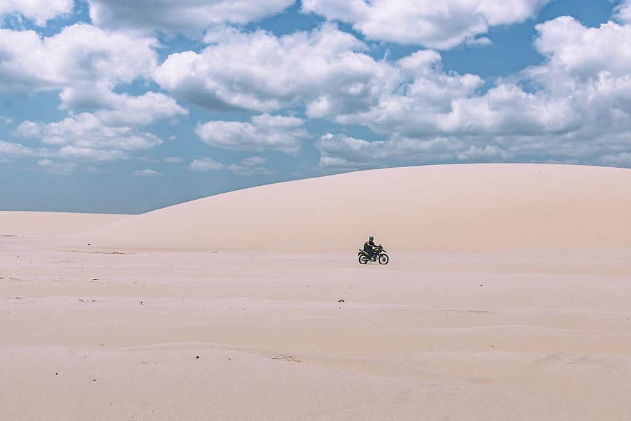 person rides on motorcycle under white sky, person riding black motorcycle on sand under cloudy sky during daytime HD wallpaper