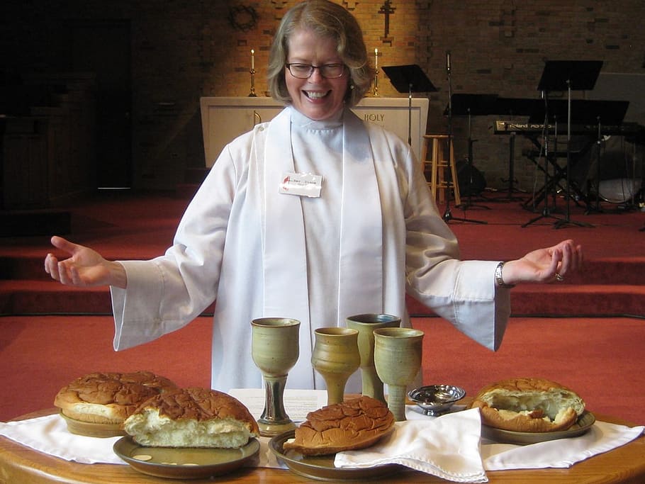 priest standing in front of chalice and leavened breads, communion
