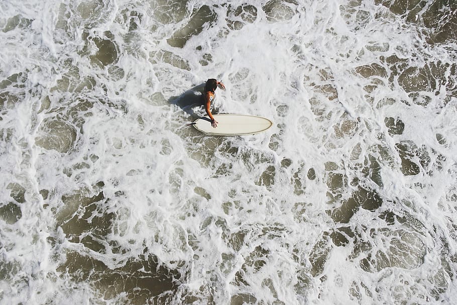 person in body of water holding surfboard, man riding surf board