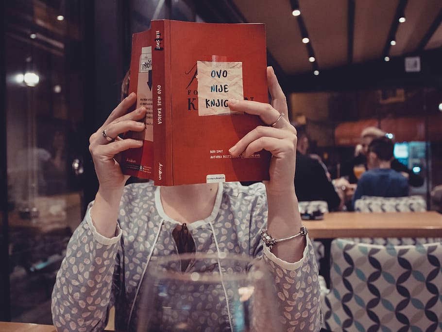 woman sitting in front of table reading book, woman holding book sitting near to table HD wallpaper