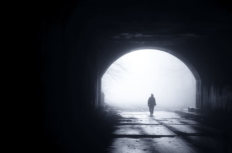 silhouette of person walking out from tunnel during daytime, silhouette of man walking from tunnel