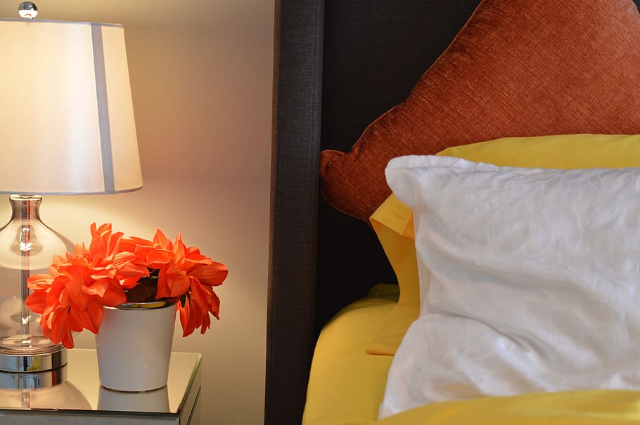 orange petaled flowers with white ceramic pot near bed with white pillow HD wallpaper