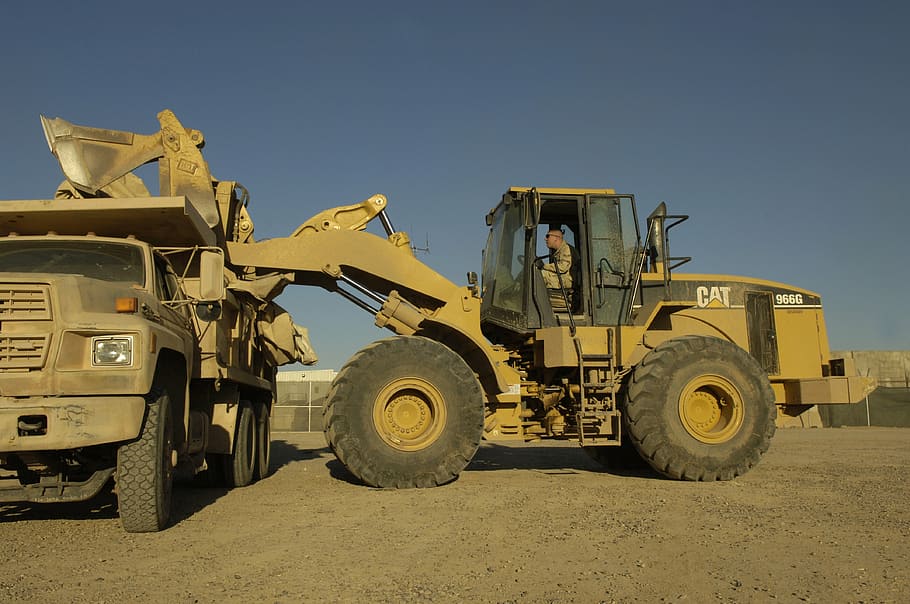 yellow Caterpillar excavator beside dump truck, heavy equipment