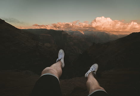 person sitting white facing cliff, person wearing white lace-up high-tops HD wallpaper