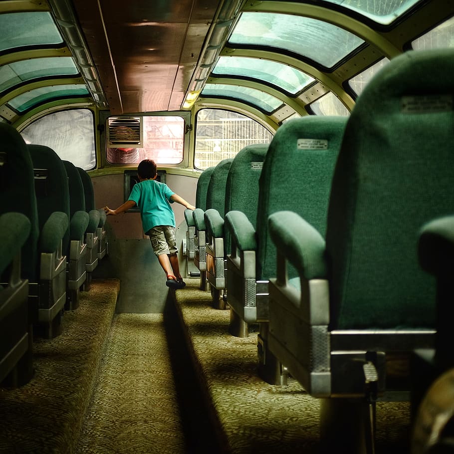 boy walking inside bus with green seats, boy inside bus holding chair HD wallpaper