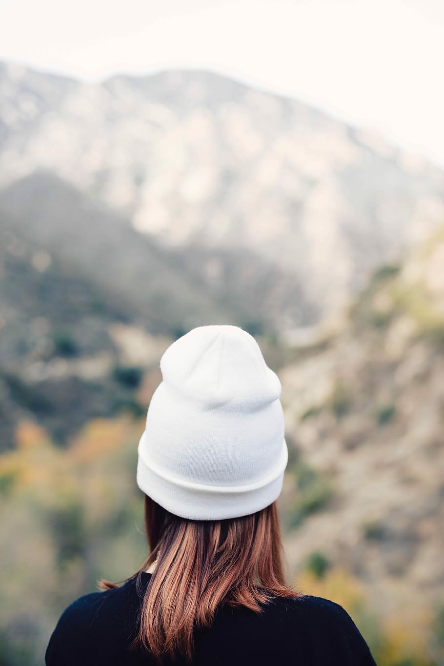 woman wearing knit hat facing through mountains, shallow focus photography of person facing mountains during daytime