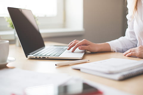 woman in white long-sleeved shirt holding gray laptop computer on brown wooden desk HD wallpaper