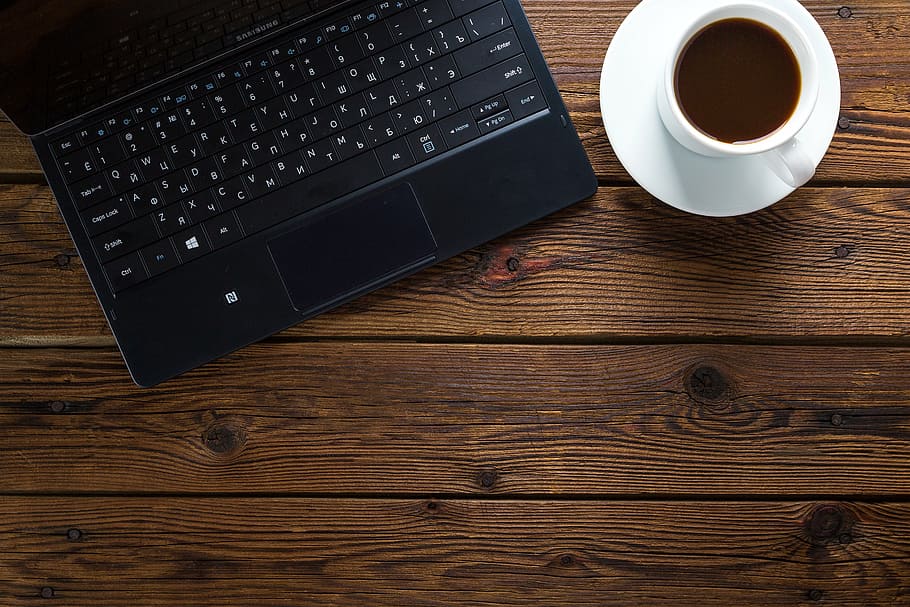 black laptop computer beside white ceramic teacup with saucer on brown wooden surface, HD wallpaper