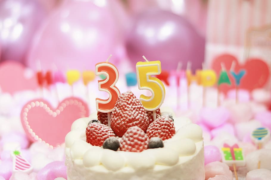 red and yellow 35-printed candle on cake with strawberries and blueberries HD wallpaper
