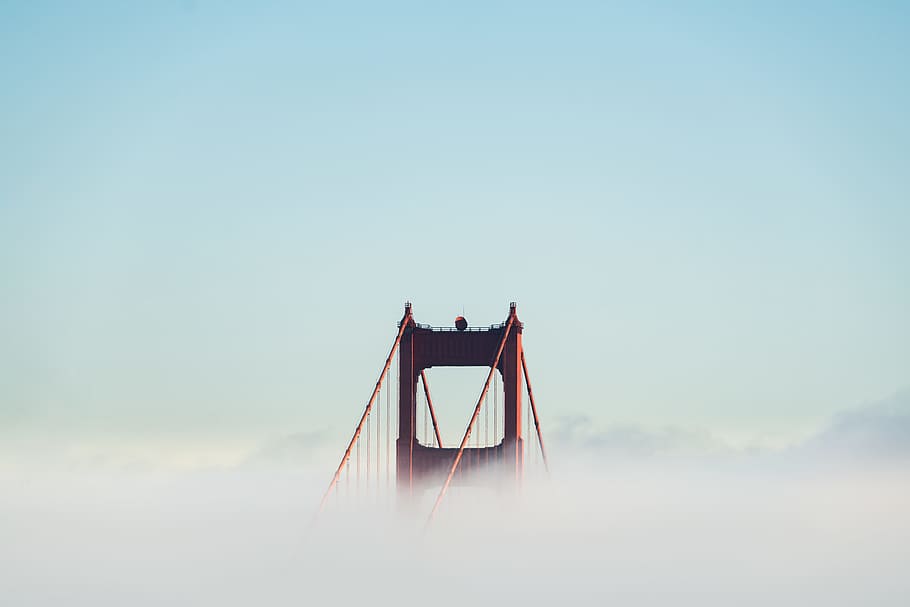 red concrete bridge surrounded by clouds, photography of bridge with fog during daytime HD wallpaper