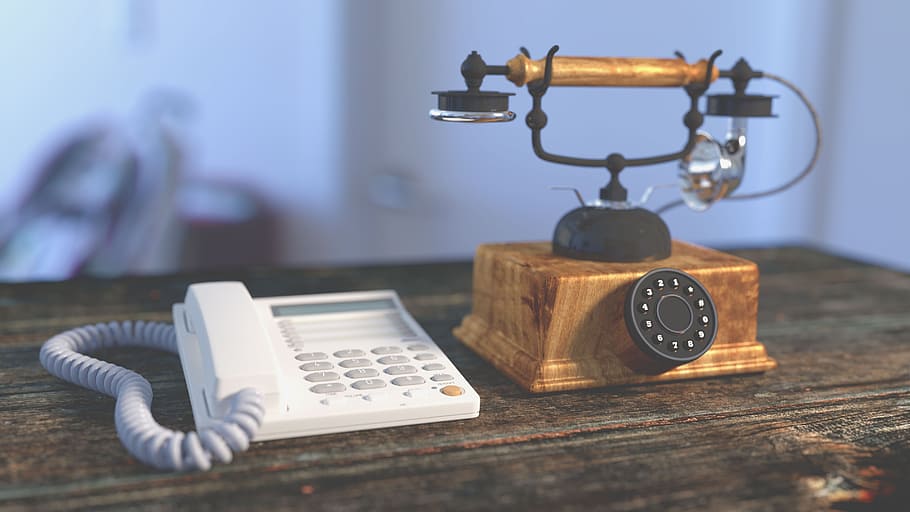 white IP telephone and brown rotary phone on top of brown board HD wallpaper