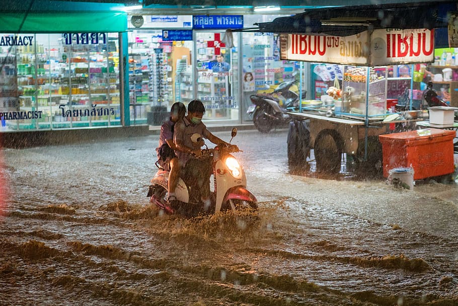 two people on motor scooter in middle of flood, rain, heavy, extreme