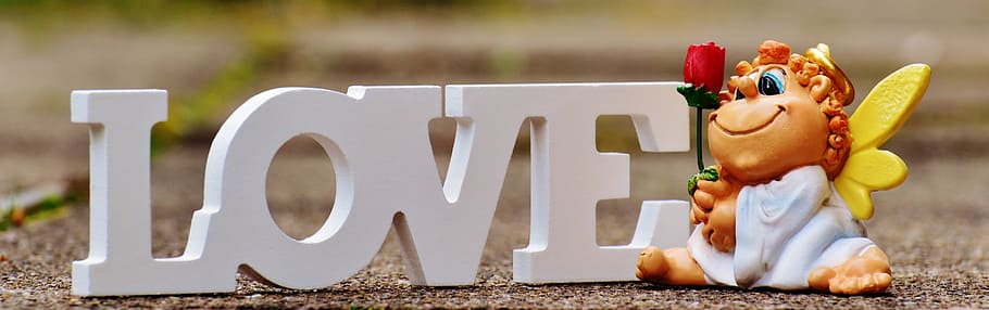 white love free standing letter and figurine holding red rose