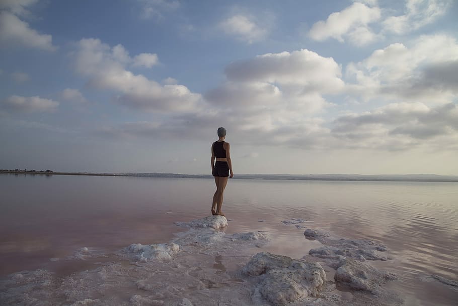 woman standing on top of rock near body of water, woman standing on iced berg HD wallpaper