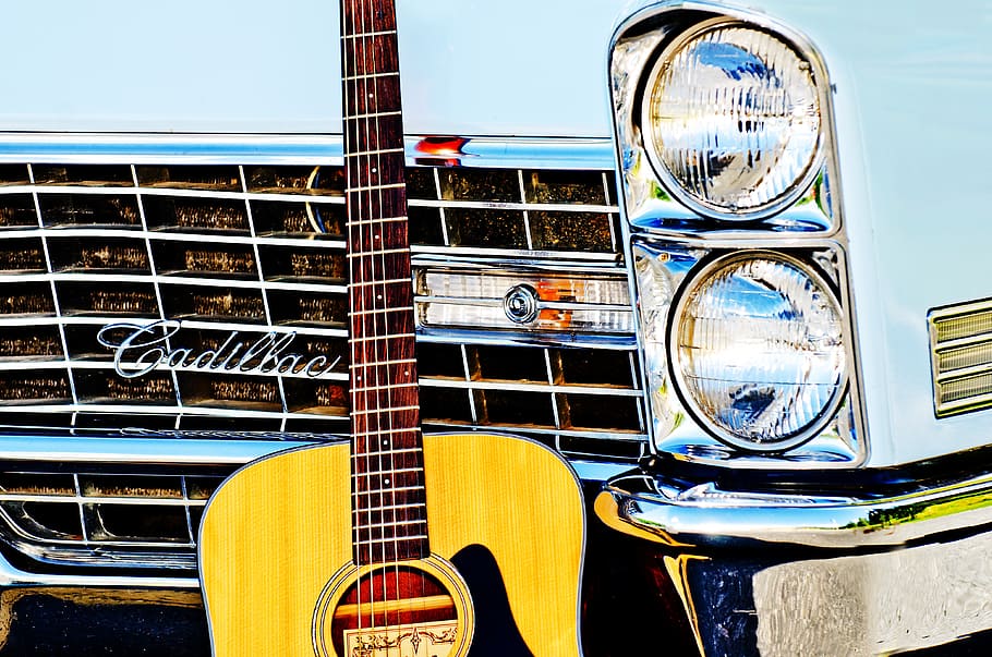 brown acoustic guitar leaning on white Cadillac car, vintage car
