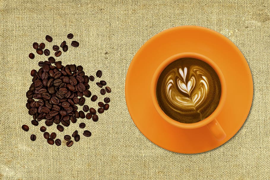 brown coffee beans near orange mug, cup and saucer, black coffee