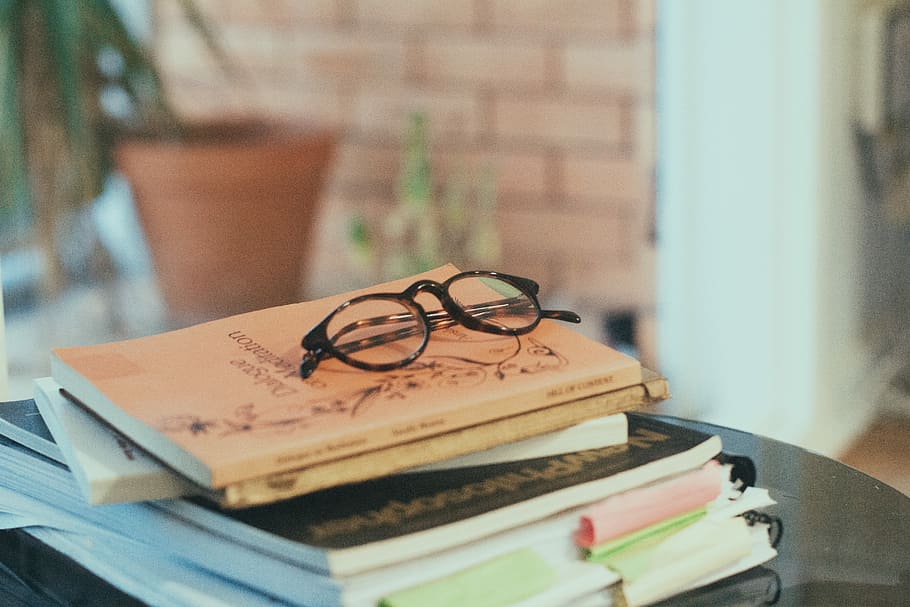 books pile on table, black eyeglasses on book, wall, plant, publication HD wallpaper