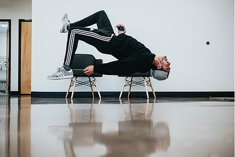 man sitting on chair near wall, man lying on two stools near white wall inside well lit room HD wallpaper