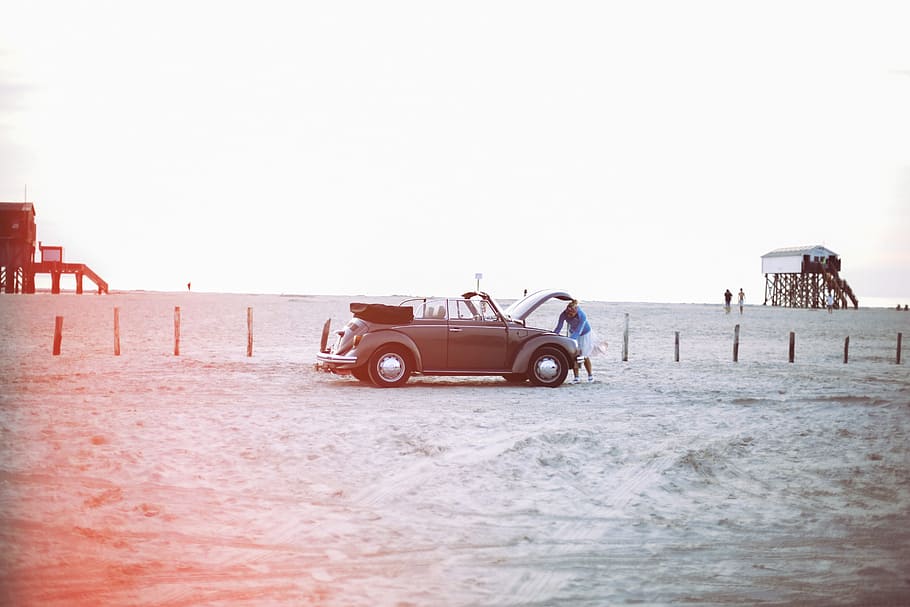woman looking to vehicle engine near peoples at daytime, driving on the beach HD wallpaper