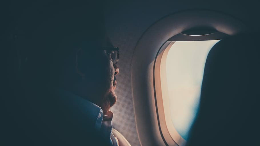 closeup photo of man wearing white collared shirt sitting beside glass window, man in white collar top and wearing eyeglasses beside of airplane window HD wallpaper