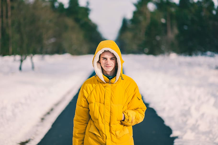 man in yellow coat walking through snow road, person wearing yellow bubble hoodie HD wallpaper