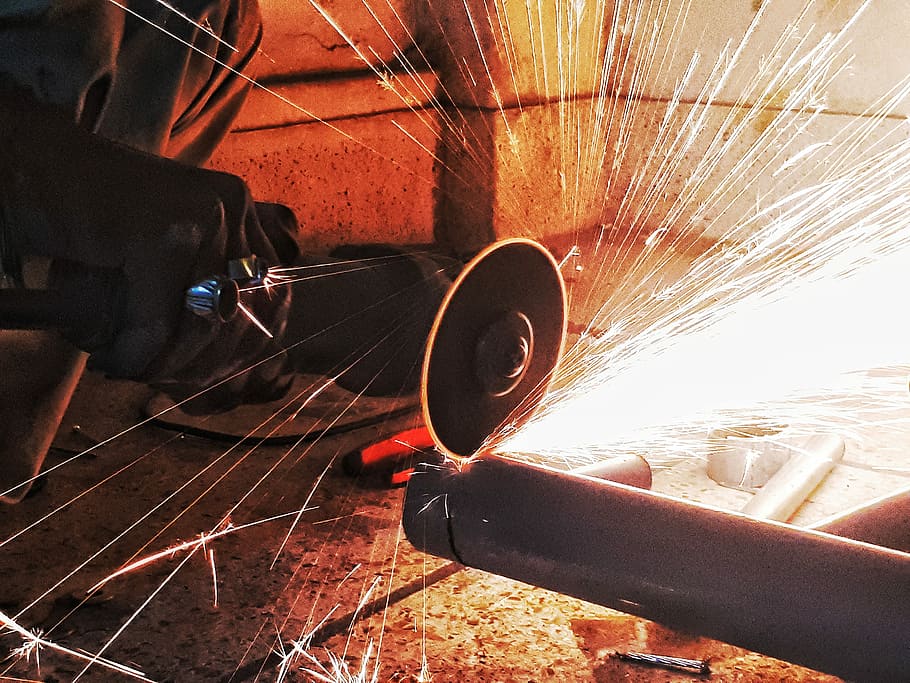 person grinding pipe steel wool photography, person doing welding