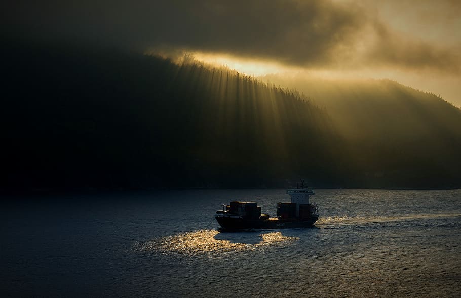 two ships on body of water under cloudy skies during golden hour, boat on body of water near silhouette of mountains during daytime HD wallpaper