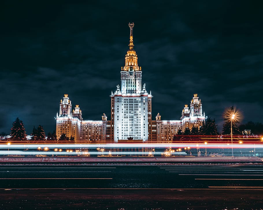 white concrete high-rise building at nighttime, time lapse photography of a white tall building HD wallpaper