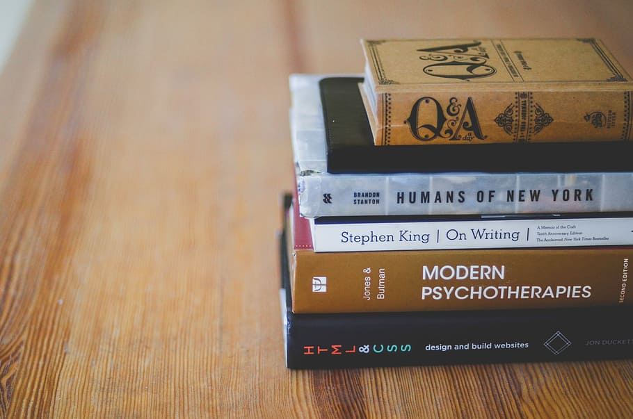 assorted reading books on table, photography of five books on wood surface