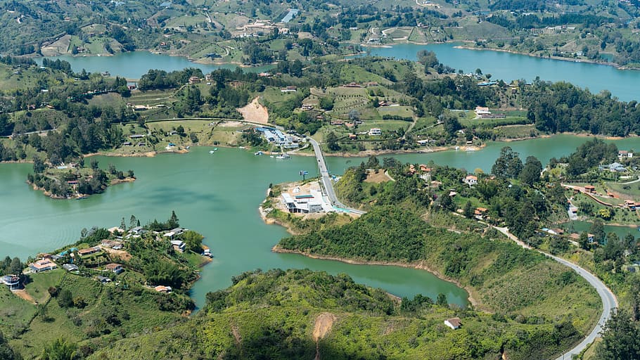 aerial photography of curved road heading towards bridge near body of water, arial photo of village