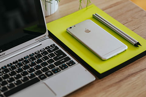 Silver Acer laptop, a white Apple iPhone and a notepad on a wooden desk HD wallpaper