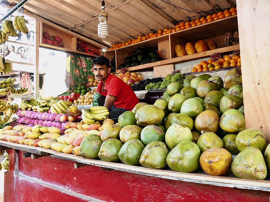 man wearing red polo shirt sitting behind fruit stand, mango HD wallpaper