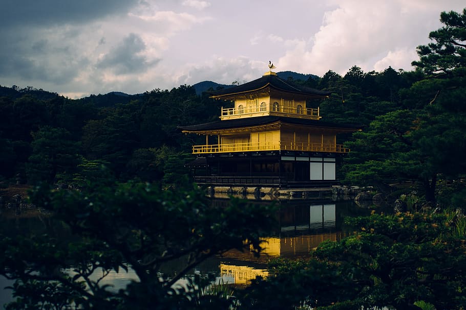 yellow and black pagoda near body of water, gold and brown pagoda temple surrounded with green trees under white clouds HD wallpaper