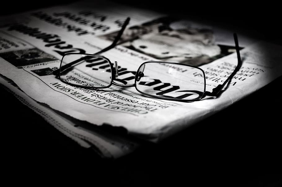 closeup photo of eyeglasses on newspaper, article, background