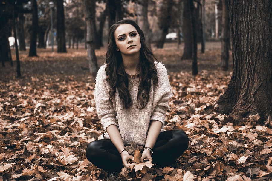 woman in gray sweater and black pants sitting on ground full of leaves, HD wallpaper