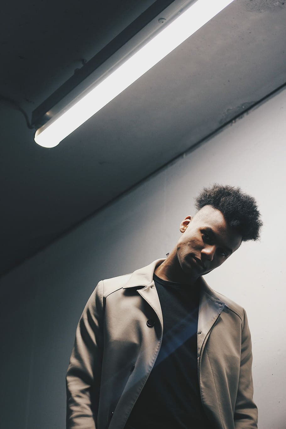man wearing gray coat near white wall, man standing near wall under the fluorescent bulb HD wallpaper