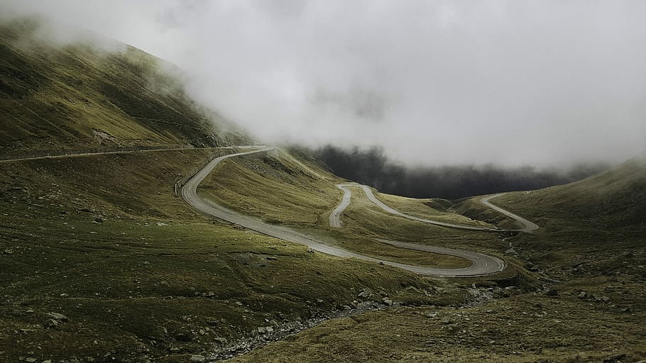 aerial photography of curved concrete road at daytime, pathway through the mountains with fog, HD wallpaper