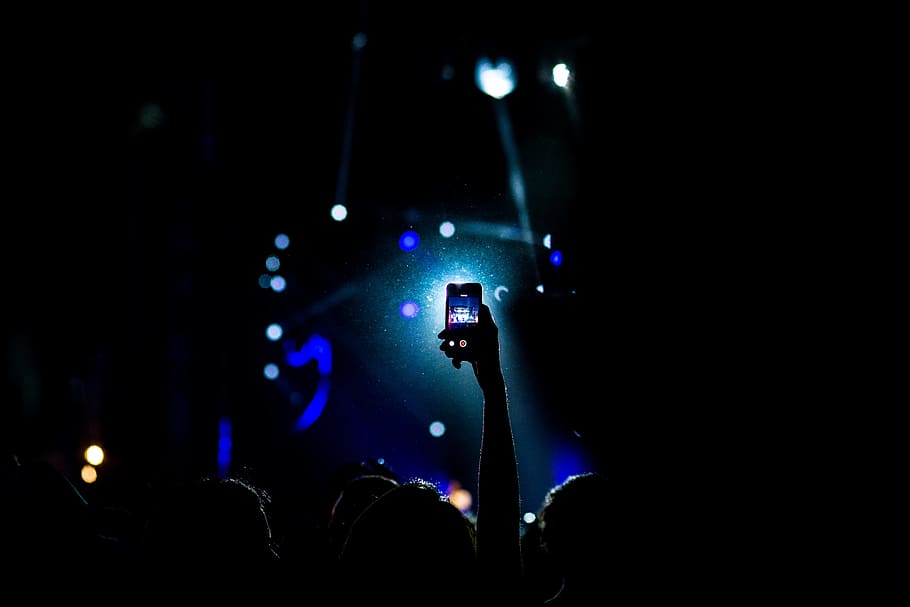 low light photography of person raising hand holding smartphone, person taking a video HD wallpaper