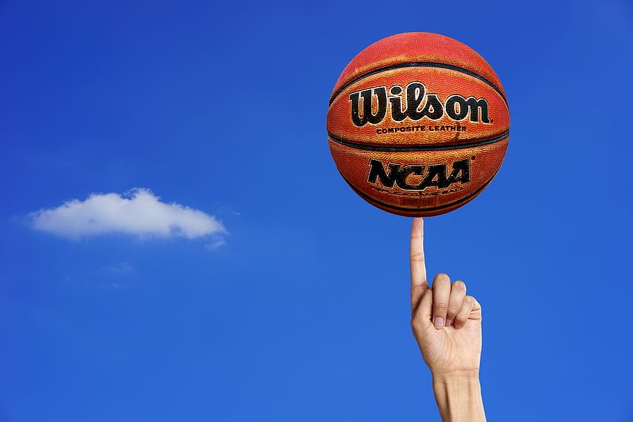 Wilson NCAA ball on left person index finger, basketball, ball game