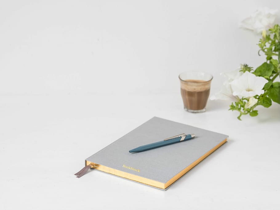 blue click pen on top of gray book near clear drinking glass, blue click pen on top of gray book HD wallpaper