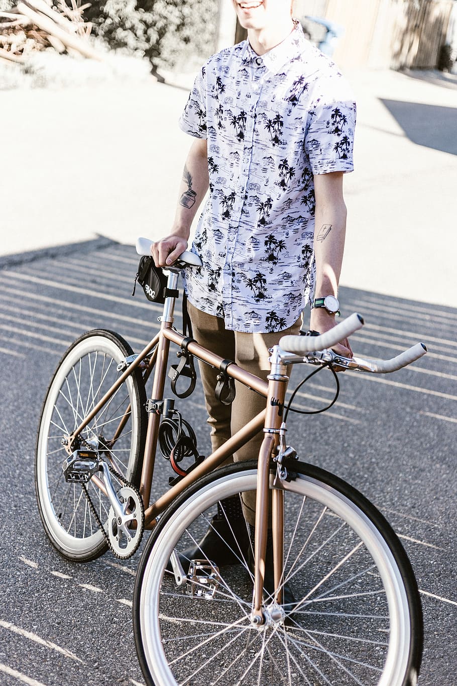 person in white and black button-up top, man holding road bike